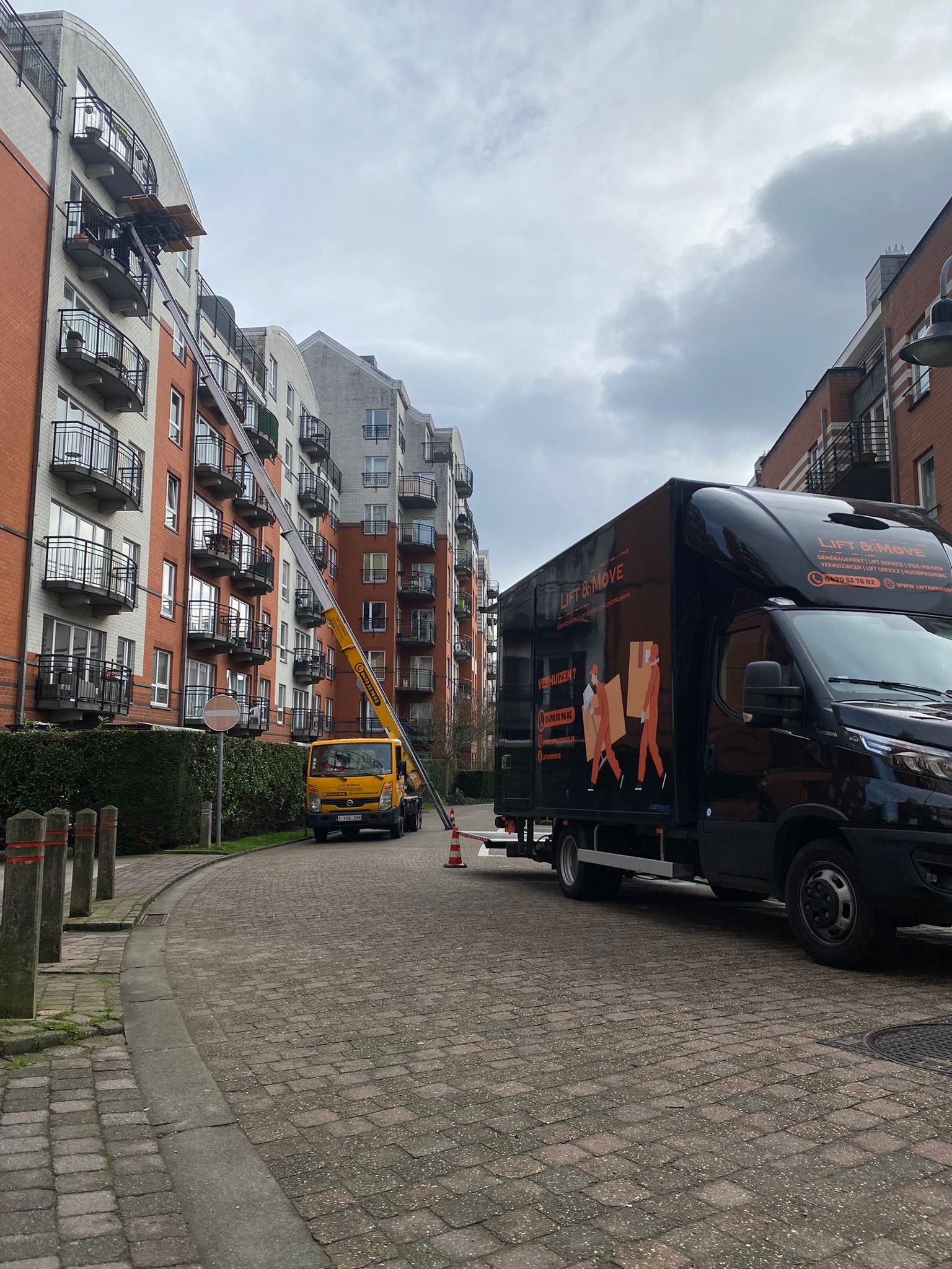 Lift Jaune et camion noir de la société Lift and Move en action dans une ruelle de Bruxelles