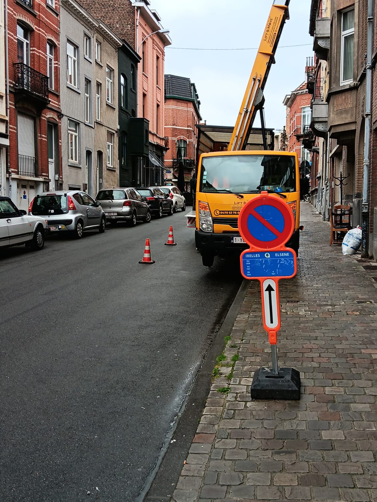 Lift en action montant des meubles dans la rue, avec le panneau de stationnement réservé par la société Lift and Move